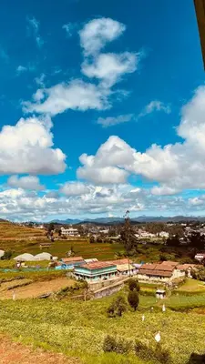 a view of a field with a building in the distance at Sunset Valley Holiday Inn in Ooty