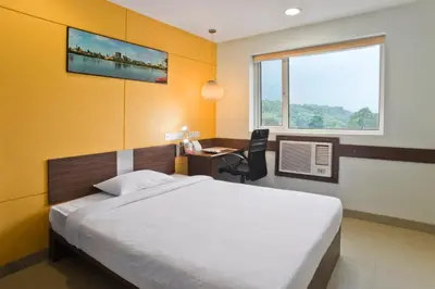 a bedroom with a bed and a desk and a window at Ginger Tirupur in Tiruppūr