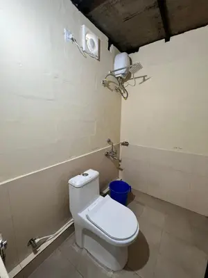 a bathroom with a white toilet and a fan at The Hillock-quiet by the Mountains in Vallikavungal