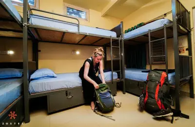 a woman standing in a room with two bunk beds at Zostel Mysore in Mysore
