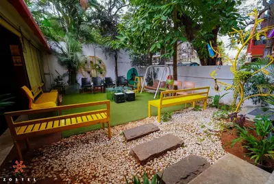 a yard with two yellow benches and chairs at Zostel Mysore in Mysore