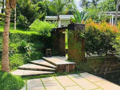 a garden with a stone walkway and a gate at Le Candles Resort in Kozhikode