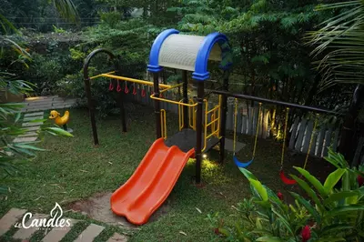 a playground with a slide in a yard at Le Candles Resort in Kozhikode