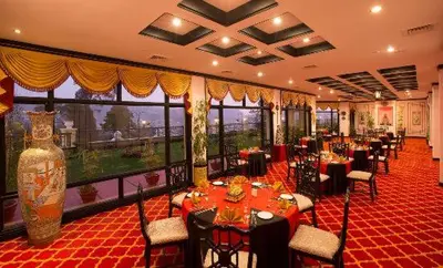 a restaurant with tables and chairs and a large window at Gem Park Ooty in Ooty