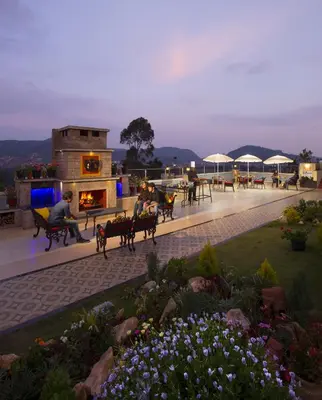 a group of people sitting on benches on a patio at Gem Park Ooty in Ooty
