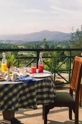 a table with food and drinks on top of a balcony at Amritara Ambatty Greens Resort in Virajpet