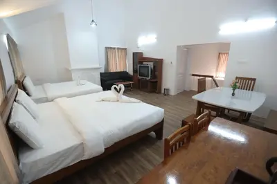 a hotel room with a bed and a table and a desk at Tiger Hill Homestay in Ooty