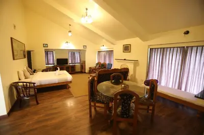 a living room with a bed and a table and chairs at Tiger Hill Homestay in Ooty