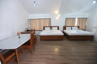 a hotel room with two beds and a table at Tiger Hill Homestay in Ooty