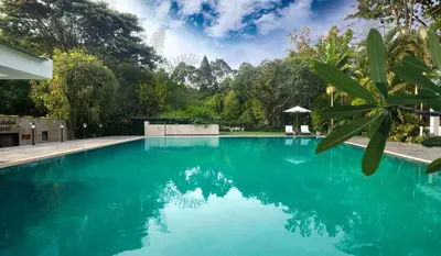 a swimming pool with blue water and trees in the background at Amanvana Spa Resort, Coorg in Kushālnagar