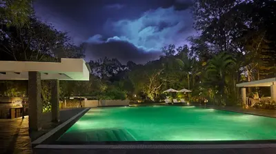 a swimming pool in a yard at night at Amanvana Spa Resort, Coorg in Kushālnagar