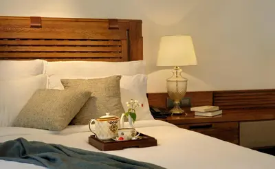 a bedroom with a bed with a wooden headboard and a table with a lamp at Amanvana Spa Resort, Coorg in Kushālnagar