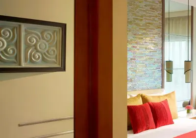 a room with a bed with red and yellow pillows at Vivanta Coimbatore in Coimbatore