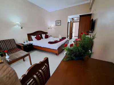 a hotel room with a bed and a living room at Hotel Preethi Classic Towers in Ooty