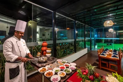 a chef standing in front of a buffet of food at Sterling Ooty Fern Hill in Ooty