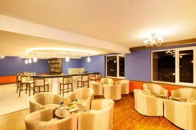 a restaurant with chairs and a bar in the background at Sterling Ooty Fern Hill in Ooty