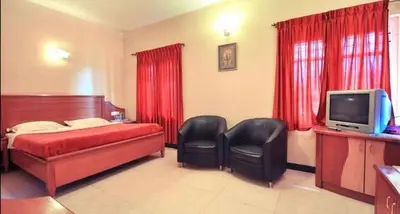 a bedroom with a bed and two chairs and a television at Hotel Silver Oak in Ooty