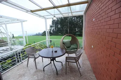 a patio with a table and chairs and a brick wall at Delightz Inn in Ooty
