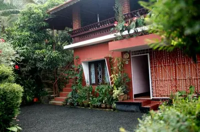 a red house with stairs and a balcony on it at The Four Seasons in Kalpetta