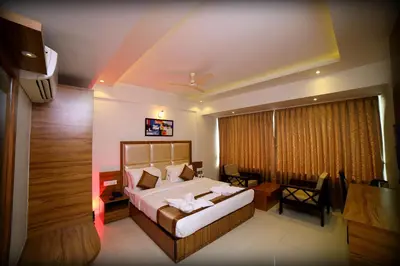 a bedroom with a bed and a desk and a table at Grand Plaza Suites in Kozhikode
