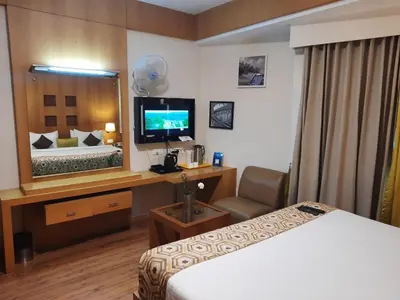 a hotel room with a bed and a television at Meadows Residency in Ooty