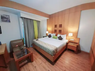 a hotel room with a bed and a chair at Meadows Residency in Ooty