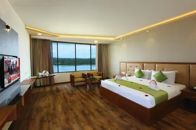 a hotel room with a large bed and a flat screen tv at The River Retreat Heritage Ayurvedic Resort in Shoranūr