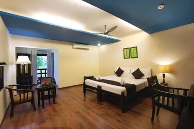 a living room with a bed and a table at The River Retreat Heritage Ayurvedic Resort in Shoranūr
