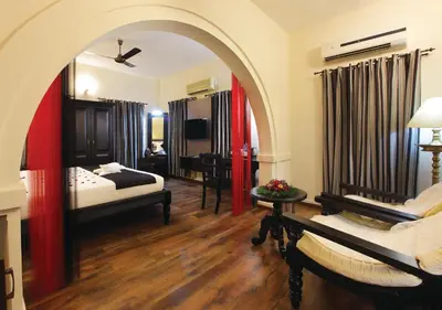 a room with a bedroom with a bed and a couch at The River Retreat Heritage Ayurvedic Resort in Shoranūr