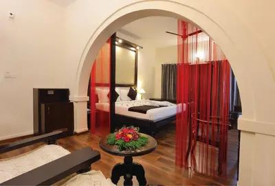 a hotel room with a bed and a table with flowers at The River Retreat Heritage Ayurvedic Resort in Shoranūr