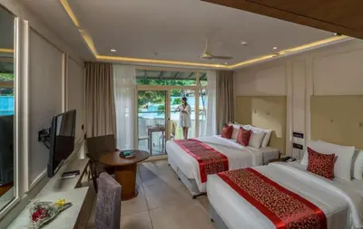 a hotel room with two beds and a television at Vythiri Village in Vythiri