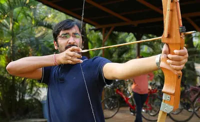 a man is holding a bow and arrow at Vythiri Village in Vythiri