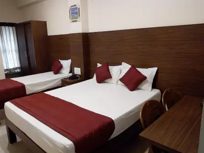 a hotel room with two beds and a table at Hotel Lovely Nest in Coimbatore