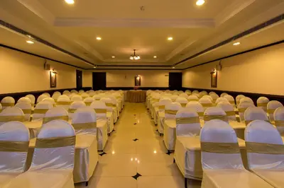 an empty hall with white chairs and tables at Kallada Regency in Irinjālakuda