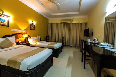 a hotel room with two beds and a desk at Kallada Regency in Irinjālakuda
