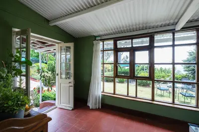 a room with green walls and windows and a porch at King's Cliff in Ooty