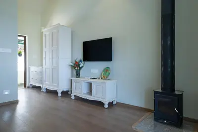 a living room with a tv and a white cabinet at King's Cliff in Ooty