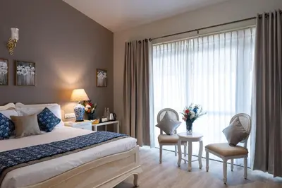 a bedroom with a bed and two chairs and a window at King's Cliff in Ooty