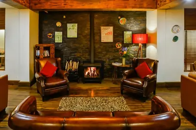 a living room with leather chairs and a fireplace at Destiny - The Farm Resort in Ooty