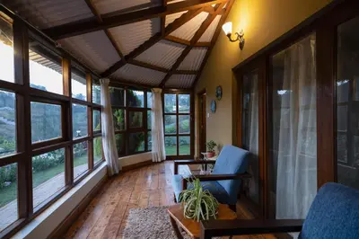 a living room with large windows and blue chairs at Sherlock in Ooty