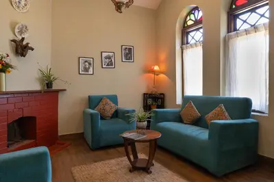 a living room with two blue chairs and a fireplace at Sherlock in Ooty