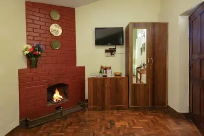 a living room with a brick fireplace and a television at Sherlock in Ooty