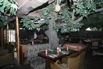 a table in a restaurant with a tree in the background at Hotel Pai Vista in Mysore