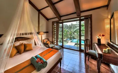 a bedroom with a bed with a mosquito net at Evolve Back Coorg in Siddapur