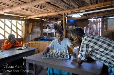 two men playing a game of chess on a table at Evolve Back Coorg in Siddapur