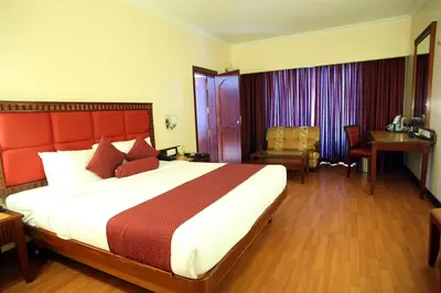 a hotel room with a large bed and a desk at Joys Palace Hotel in Trichūr