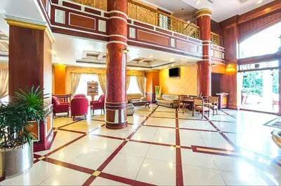 a lobby with columns and tables and chairs at Joys Palace Hotel in Trichūr