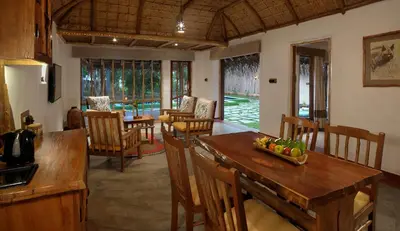 a kitchen and dining room with a table and chairs at Evolve Back Kabini in Begūr