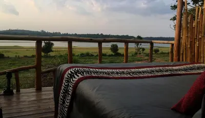 a bed on a deck with a view of a field at Evolve Back Kabini in Begūr