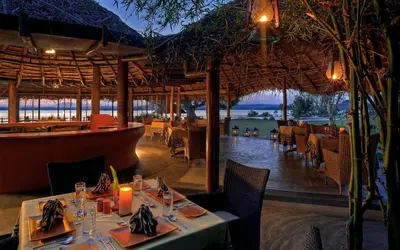 a restaurant with tables and chairs with a view of the ocean at Evolve Back Kabini in Begūr